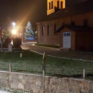 Zapalona choinka na parkingu przed kościołem  zapowiada zbliżające się święta Bożego Narodzenia. 