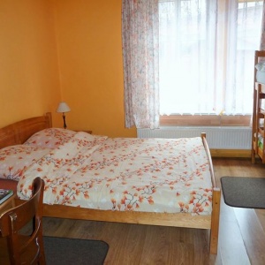 Duży pokój  pomarańczowy z łazienką . łóżko piętrowe i duże małżeńskie solidne drewniane meble. 