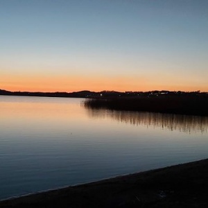 Piękny zachód słońca nad jeziorem Kłodno - trzcina wodna ślicznie odbija się w  spokojnej tafli jeziora.  Domostwa wsi  Chmielno rozświetlone światłem elektrycznym.! 